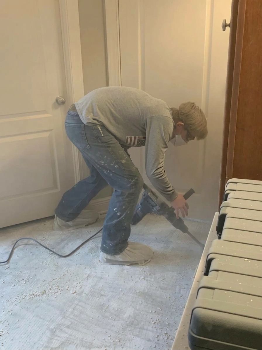 Matthias on a job, chiseling old grout off a floor with a hammer drill